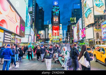 Am Times Square, umgeben von hellen Plakaten und Lichtern der Stadt, sind Touristen und Künstler in der Nacht zu sehen. New York. USA. Stockfoto