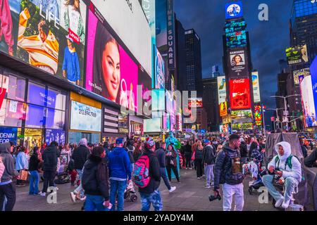 Times Square bei Nacht mit Touristen, Plakaten und Straßenkünstlern unter den leuchtenden Lichtern der Stadt New York. USA. Stockfoto