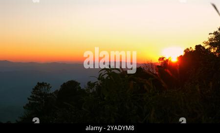 Atemberaubender Sonnenaufgang erleuchtet den Himmel über der ruhigen Berglandschaft, Stockfoto