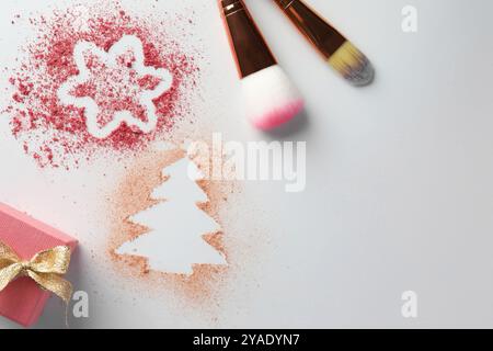 Weihnachtsdekorationen aus Puder und Rouge, Geschenkbox und Make-up-Pinsel auf weißem Hintergrund, flach gelegt. Leerzeichen für Text Stockfoto