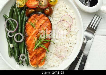 Leckeres gegrilltes Lachssteak mit Reis und Gemüse serviert mit Sojasauce auf weißem Holztisch, flach gelegt Stockfoto