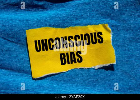 Unbewusste Vorurteile auf gerissenem gelbem Papierstück mit blauem Hintergrund. Konzeptuelles unbewusstes Vorurteil-Symbol. Kopierbereich. Stockfoto