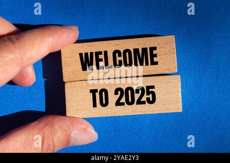 Willkommen bei 2025 Nachricht auf Holzblöcken mit blauem Hintergrund. Konzeptionelles Willkommen bei 2025 Symbol. Kopierbereich. Stockfoto