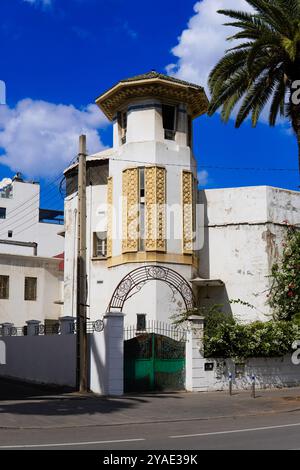 Ein historisches Gebäude mit einem kunstvollen Turm mit aufwändigen goldenen Designs steht vor einem hellblauen Himmel. les tourelles , casablanca, Marokko Stockfoto