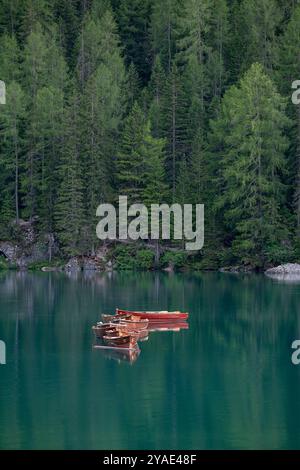 Holzboote, die auf smaragdgrünen Gewässern im Herzen des Pragser Wildsees schwimmen Stockfoto