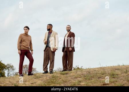 Drei modische Männer posieren zusammen in einem malerischen Feld und genießen die Schönheit des herbstlichen Charmes. Stockfoto