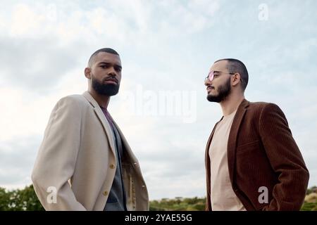 Zwei gutaussehende Männer, elegant für den Herbst gekleidet, genießen die Schönheit der Natur in einem ruhigen Herbstfeld. Stockfoto