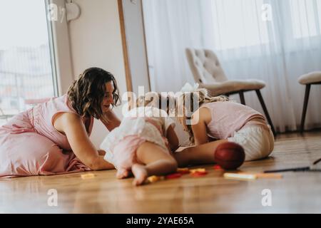 Mutter und Töchter spielen zusammen auf dem Boden zu Hause, verbinden sich und verbringen gute Zeit Stockfoto