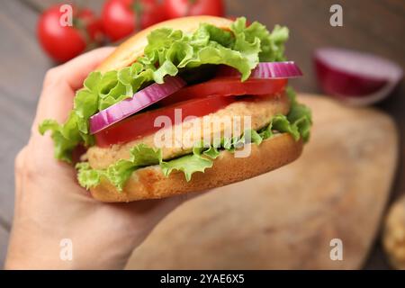 Frau mit vegetarischem Burger mit Kichererbsenkotelett am Tisch, Nahaufnahme Stockfoto