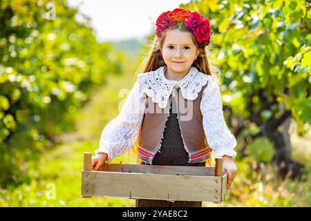 Multiethnische Frau, erfahrene Weinbauerin, Winzer, Weinbauerin, die eine Holzkiste mit frischer Herbsternte von Bio-Trauben und Küken hält Stockfoto