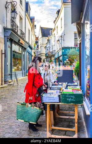 Frauen, die in Kästen vor dem Ladengeschäft in der Innenstadt gebrauchte Bücher Bücher durchsuchen - Loches, Indre-et-Loire (37), Frankreich. Stockfoto