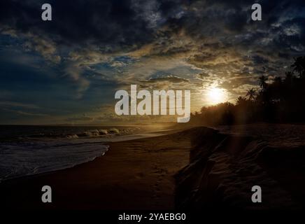 Strand in Sri Lanka (Ceylon) mit den Wellen und Sandküste, Sonnenuntergang oder Sonnenaufgang Landschaft mit schönen dramatischen Himmel. Blauer Indischer Ozean. Stockfoto