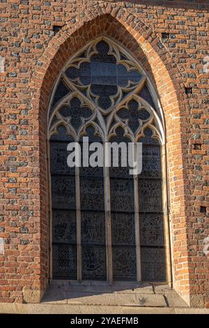 Bogenfenster im gotischen Stil mit Buntglas an einer gemauerten Kirchenwand bei Nachmittagssonne. Konzept der historischen Architektur, religiöser Bau Stockfoto