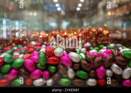 Viele Süßigkeiten in bunten Paketen am Schaufenster. Farbige Bonbons in Form von Eiern. Stockfoto