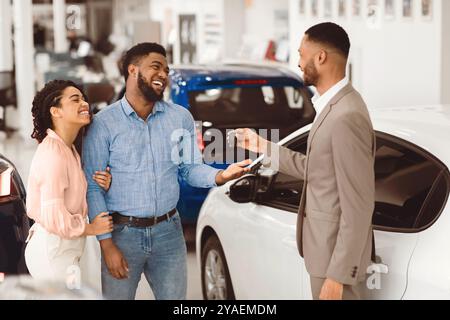 Paare, Die Ein Auto Kaufen Und Den Schlüssel Vom Verkäufer Im Auto-Showroom Holen Stockfoto