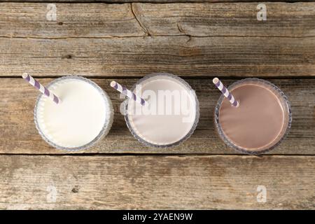 Verschiedene leckere Proteincocktails in Gläsern auf Holztisch, flach gelegt Stockfoto