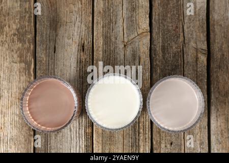 Verschiedene leckere Proteincocktails in Gläsern auf Holztisch, flach gelegt. Leerzeichen für Text Stockfoto