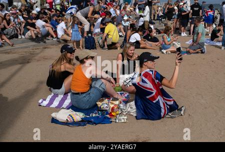 Barcelona, Spanien. Oktober 2024. Anhänger des britischen Teams Ineos folgen den Segelrennen vom Strand aus. Der zweite Tag des America's Cup Finales fand heute in Barcelona statt. Die Fans der beiden Teams Emirates und Ineos konnten das Rennen von den Stränden und Bars von Barceloneta aus verfolgen. (Foto: Paco Freire/SOPA Images/SIPA USA) Credit: SIPA USA/Alamy Live News Stockfoto