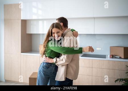 Alles Gute zum Umzugstag. Liebevolles verheiratetes Paar mit Nähe, umarmt Spaß und packt Kisten in einem neuen Zuhause aus. Stockfoto