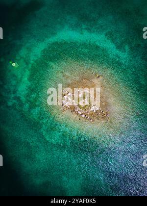 Blick von oben nach unten auf die kleine Felseninsel, umgeben vom flachen Meer in der Bucht von Rogoznica, Kroatien Stockfoto