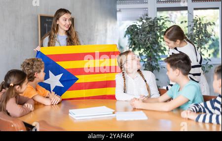 Geografie-Unterricht in der Schule - der Lehrer spricht über Katalonien und hält die Flagge in seinen Händen Stockfoto