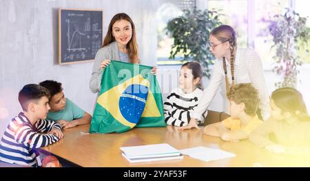 Die Lehrerin hält die Flagge Brasiliens in der Hand und erzählt den Schülern von ihrem Land Stockfoto