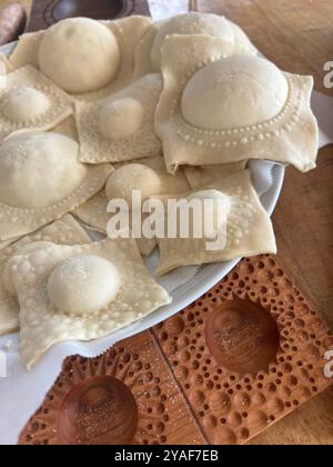 Handgefertigte Ravioli auf einem Teller, die die komplizierten Details der Teig- und Holzformen in einer rustikalen Küche hervorheben Stockfoto