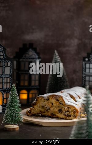 Weihnachtsstollen in Weihnachtsbeleuchtung und Dekoration. Traditionelles süßes Obstbrot mit Puderzucker festliches Gebäck Dessert. Holiday Baking Food Konzept. Stockfoto