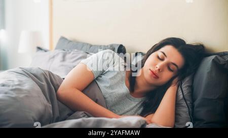 Ruhiger Morgen. Schlafende Frau. Faules Wochenende. Ruhige Frau unter Decke schließe die Augen, die in weichen Bettlaken liegen, hell im Zimmer. Stockfoto