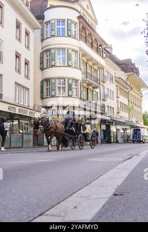 Eine Pferdekutsche fährt durch eine urbane Straße mit historischen Gebäuden, Brienzersee, Interlaken, Schweiz, Europa Stockfoto