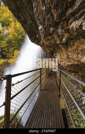 Ein Wanderweg mit Metallgeländern führt entlang eines Wasserfalls unter einem Felsvorsprung, Brienzersee, Giessbach Wasserfall, Schweiz, Europa Stockfoto