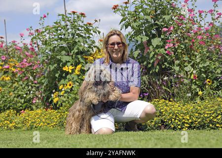 Die Frau nimmt Lhasa Apso mit auf einen Spaziergang im Park Stockfoto