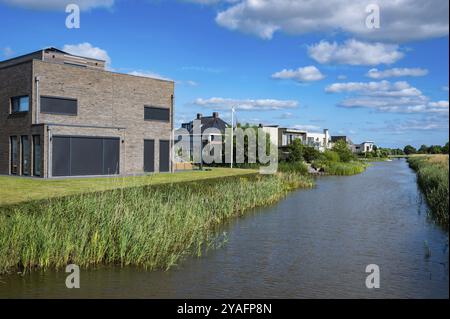 Groningen, Niederlande, 07 20 2022, zeitgenössische Landhaushäuser am Wasser umgeben von Natur über blauem Himmel in den Vororten Europas Stockfoto