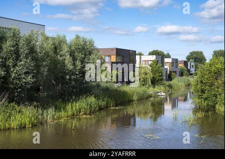 Groningen, Niederlande, 07 20 2022, zeitgenössische Landhaushäuser am Wasser umgeben von Natur über blauem Himmel in den Vororten Europas Stockfoto