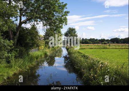 Creek rund um das Dorf Zwolle, Gelderland, Niederlande mit grünen Bäumen, die sich gegen den blauen Himmel spiegeln Stockfoto