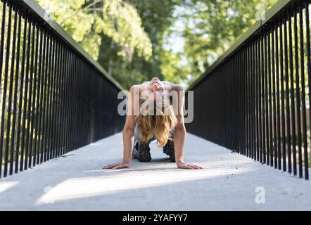 Sportliche Pose eines attraktiven 22-jährigen blonden Mädchens auf einer Fußgängerbrücke, Belgien, Europa Stockfoto