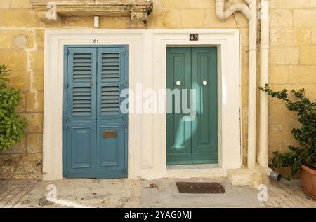 Valletta, Malta, 01 06 2022: Zwei grüne Holztüren und eine gelbe Fassade eines traditionellen Wohngebäudes, Europa Stockfoto