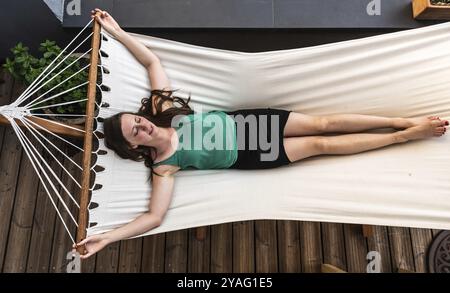 Attraktive weiße schlanke 30-jährige Dame, die in einer Hängematte in ihrem Garten liegt, Laeken, Belgien, Europa Stockfoto