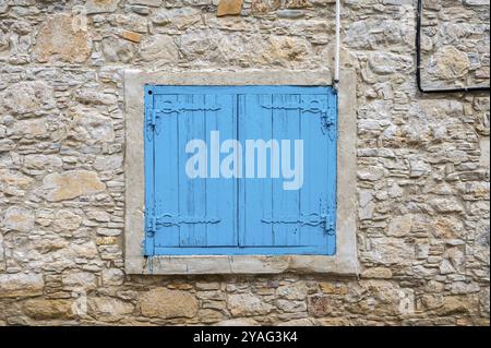 Lofou, Limassol District, Zypern, 24. März 2023, strukturierte Ziegelsteinmauer und blaue Fensterläden, Europa Stockfoto