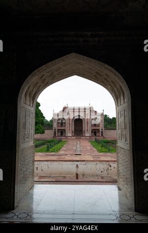 Atemberaubender Blick auf ein mogul-Mausoleum durch ein aufwendig geschnitztes Bogenportal, das die Pracht der indischen Architektur zeigt Stockfoto