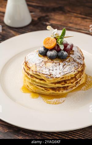 Pfannkuchen mit Früchten und Ahornsirup auf einem weißen Teller Stockfoto