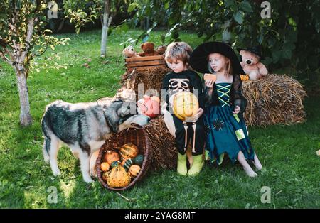 Halloween-Kinder genießen im Herbstpark auf dem Feld. Halloween auf dem Land. Kinder, Schwester und Bruder mit Kürbis, gekleidet wie Skelett und Stockfoto
