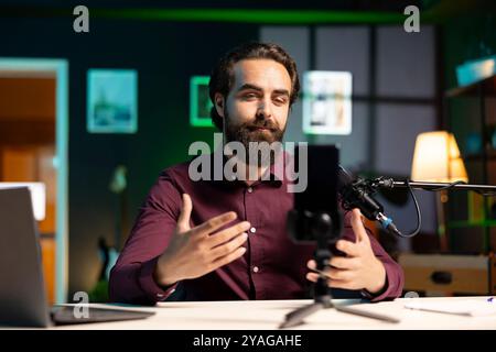 ASMR Artist verwendet hochwertiges Mikrofon und Smartphone auf einem Stativ im Studio, um Anti-Stress-Videos zu machen und Kribbeln zu flüstern. Mann, der professionelles Mikrofon und Mobiltelefon verwendet, um Inhalte zu filmen, die zum Schlafen einladen Stockfoto