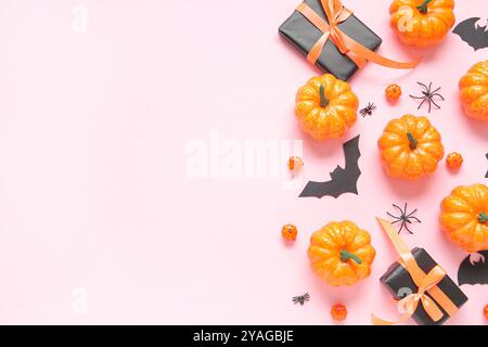 Komposition mit Geschenkboxen, Kürbissen, Fledermäusen und Spinnen auf pinkfarbenem Hintergrund. Das Konzept der Halloween-Feier Stockfoto