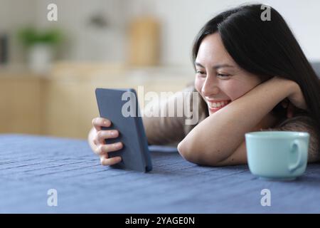 Glückliche asiatische Frau, die Eierstöcke in der Küche zu Hause liest Stockfoto