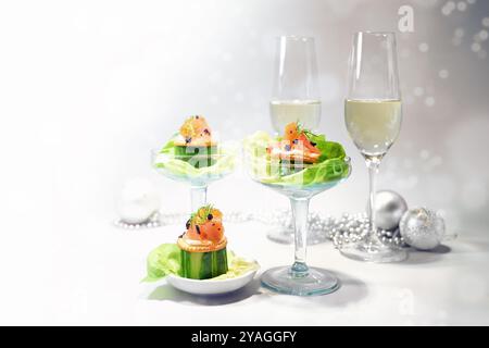 Vorspeise aus Räucherlachs, Gurke, Kaviar und Salat, zwei Sektgläser und Weihnachtsdekoration, festlicher Snack zu Weihnachten oder Neujahr, Cop Stockfoto