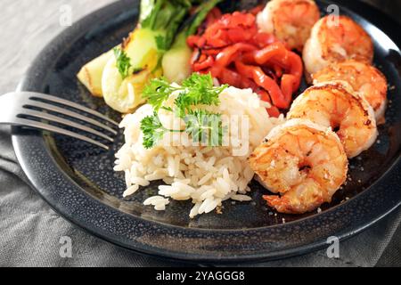 Gebratene Garnelen oder Garnelen mit Reis und Gemüse auf einem dunklen Teller, hausgemachte asiatische Mahlzeit, Kopierraum, ausgewählter Fokus, enge Schärfentiefe Stockfoto