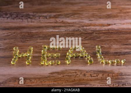 Eine hölzerne Oberfläche mit dem Wort "HEILEN", geschrieben mit gelben Pillen. Die Buchstaben bestehen aus kleinen, runden Objekten. Stockfoto