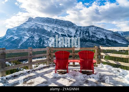 Rote adirondack-Stühle blicken an schneebedeckten, sonnigen Wintertagen über den Mount Rundle. Banff National Park wunderschöne Landschaft. Hoodoos Aussichtspunkt, Kanadische Rocky Mountains. Stockfoto