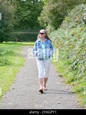 Eine Seniorin, die im Herbst 2024 am Seeufer in Saint-Fraimbult, Normandie, Nordwestfrankreich, Europa spaziert Stockfoto